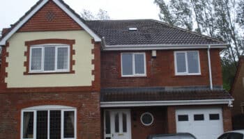 front of brick house with two cars